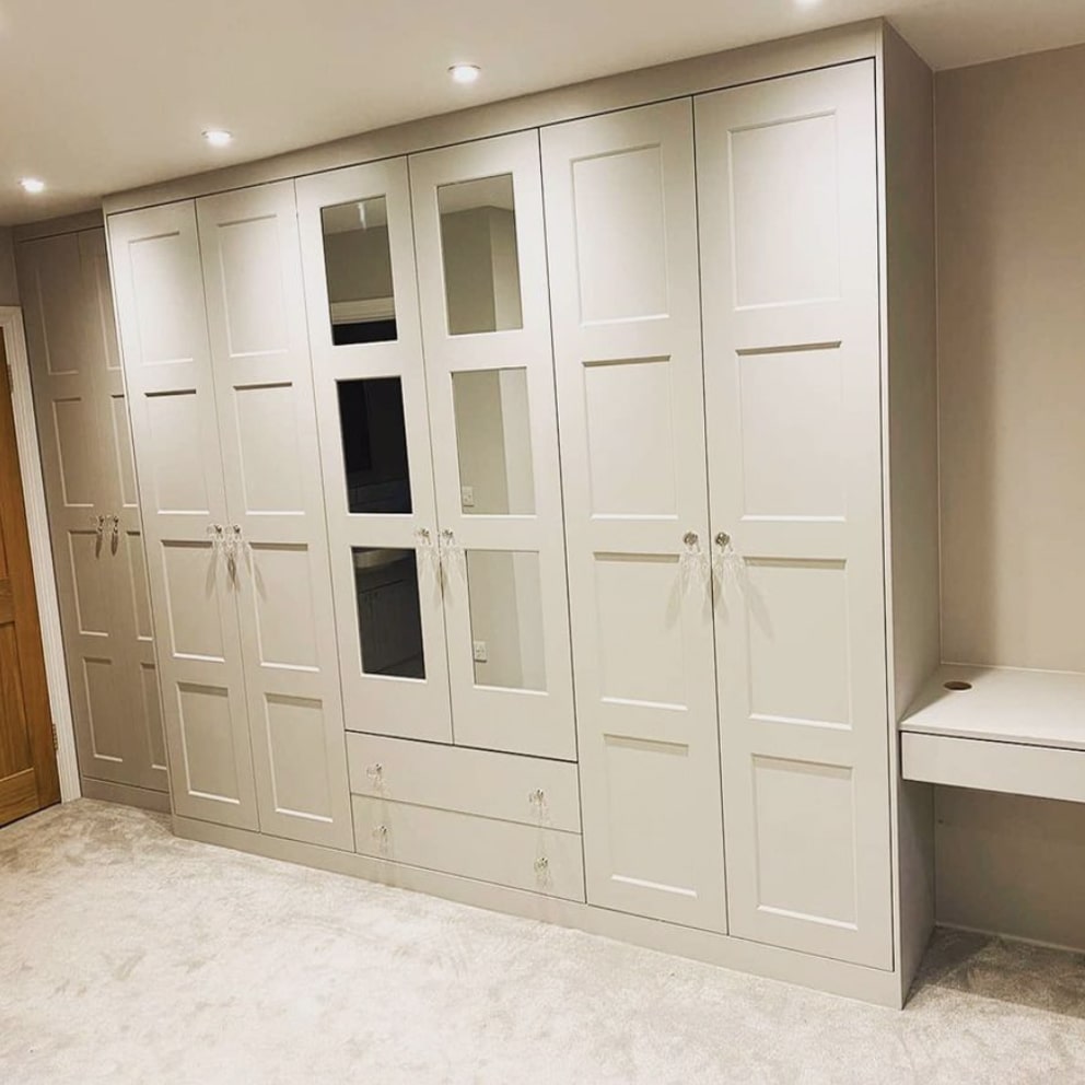 Cream eight-door fitted wardrobes with mirrored centre doors