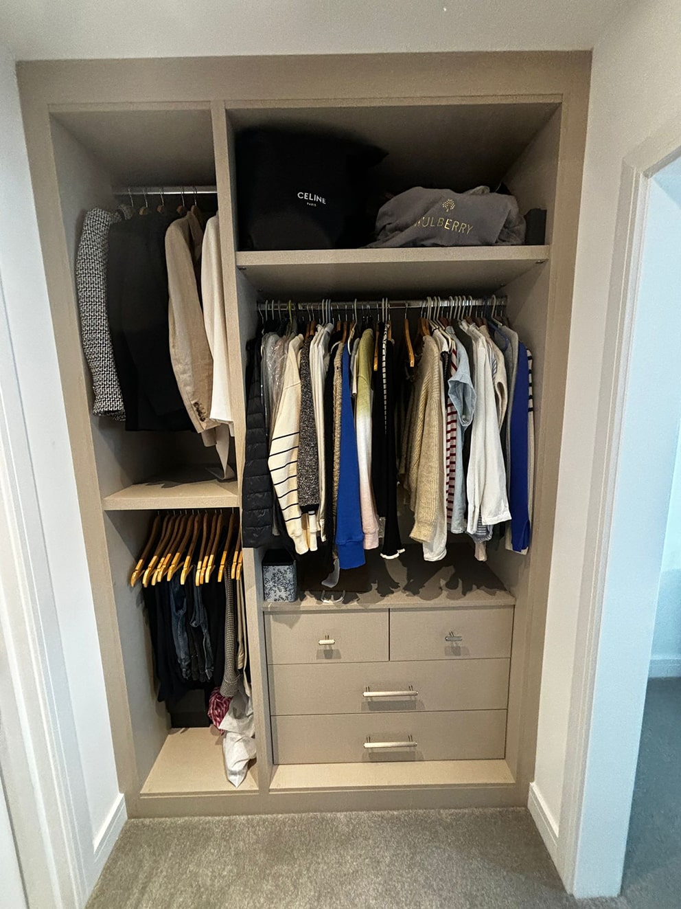 Open alcove wardrobe with hanging clothes and drawers