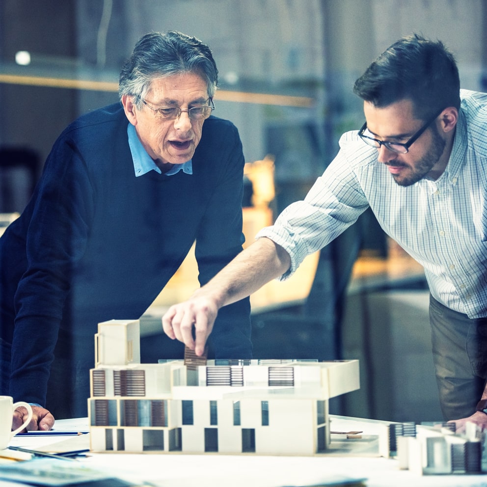 Two architects examining a scale model of a new commercial development