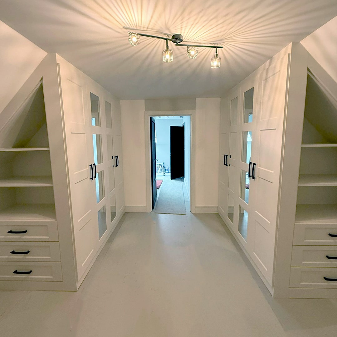 White fitted dressing room installed by DAY & KNIGHT in clients loft space with twin angled ceiling fitted wardrobes