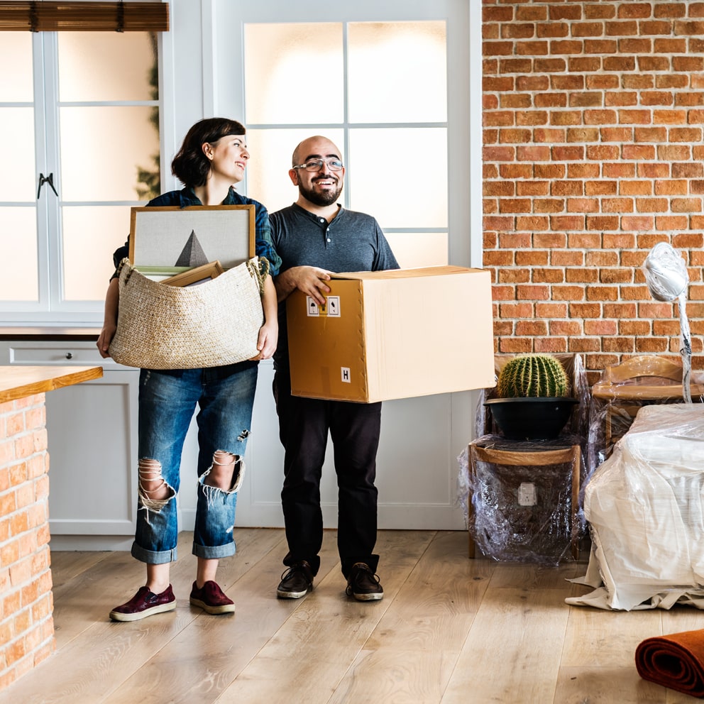 Couple standing in living room holding boxes, wondering how to get better storage in their new home
