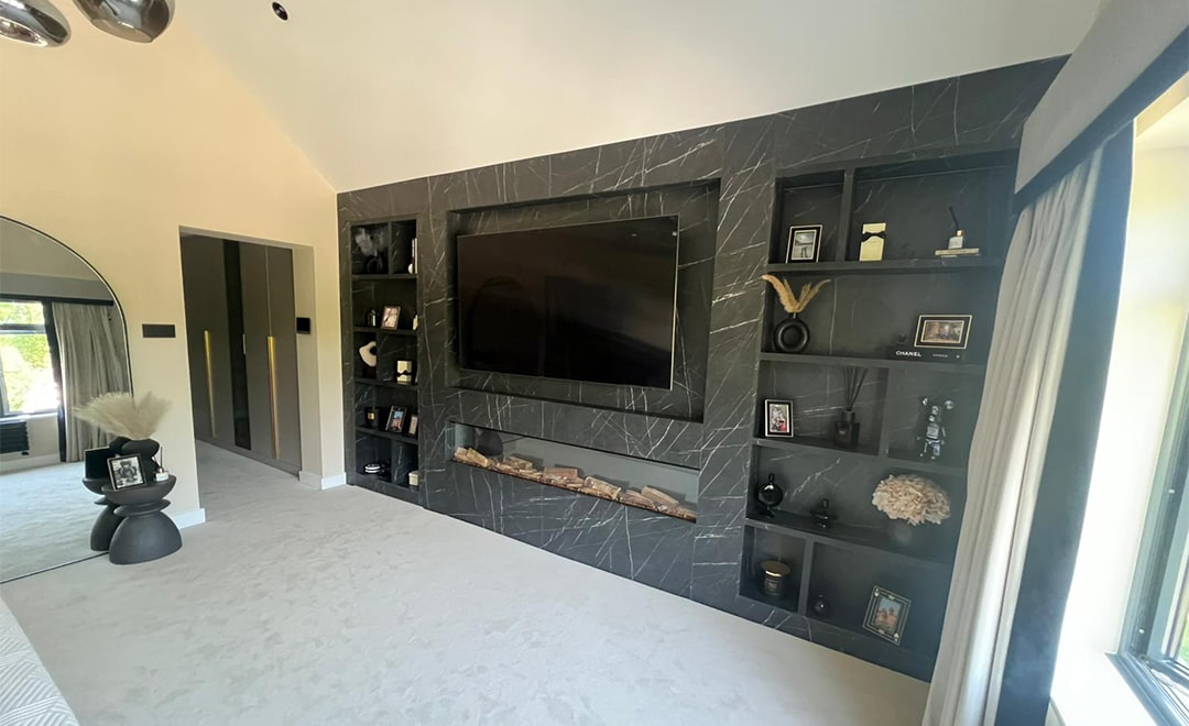 A bespoke built-in tv media wall with a secret entrance and integrated fireplace finished in Black Pietra Grigia completed by DAY & KNIGHT