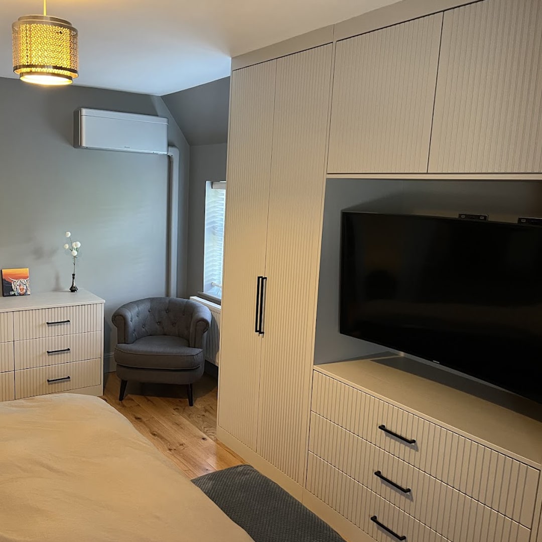 Cream fitted wardrobes, TV unit and drawers in bedroom