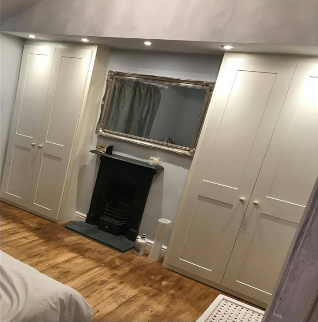Cream shaker wardrobes flanking a black fireplace with mirror