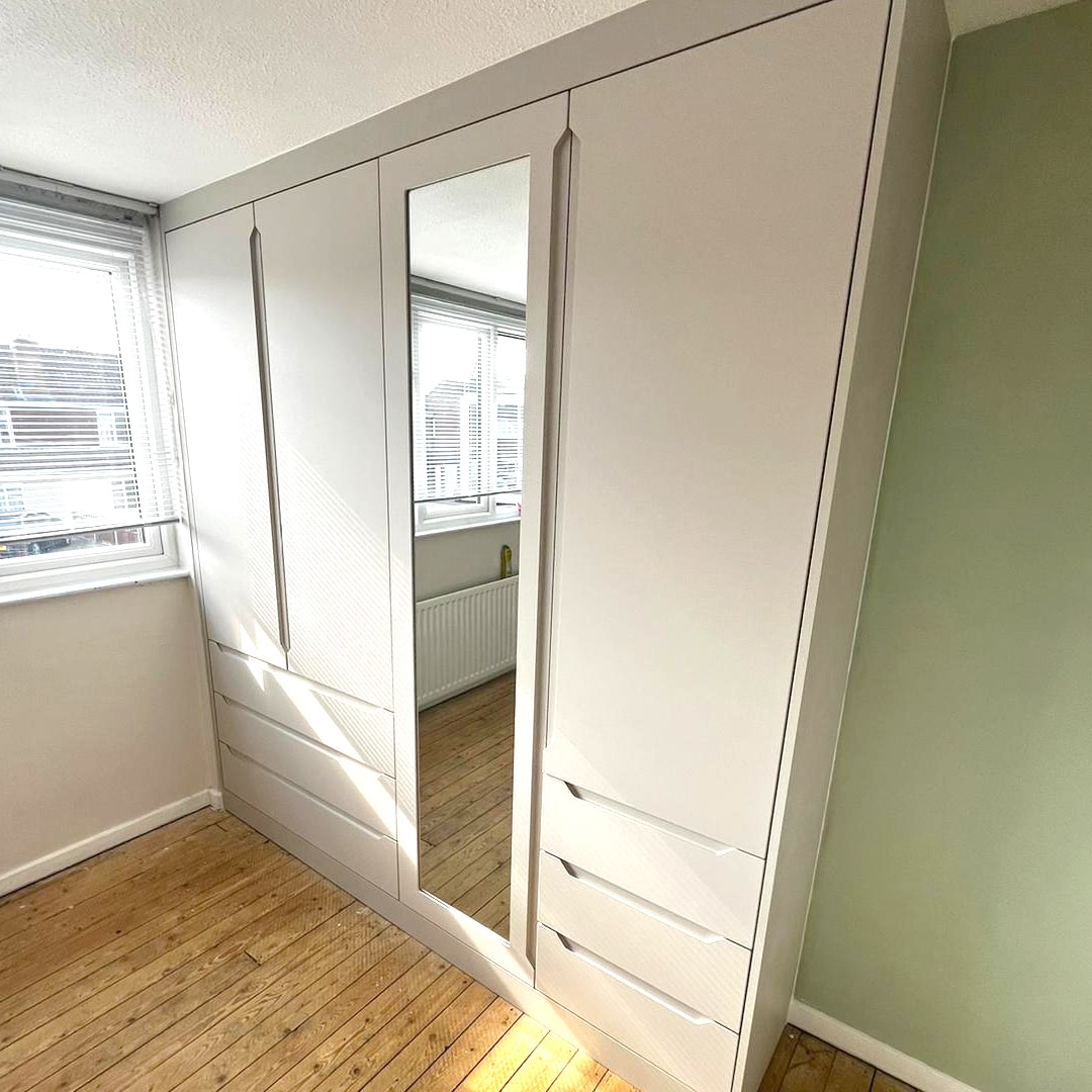Light grey handleless fitted wardrobes with full-height mirrored doors and drawers