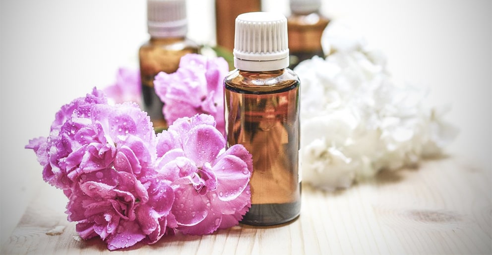 Amber essential oil bottles beside pink and white flowers