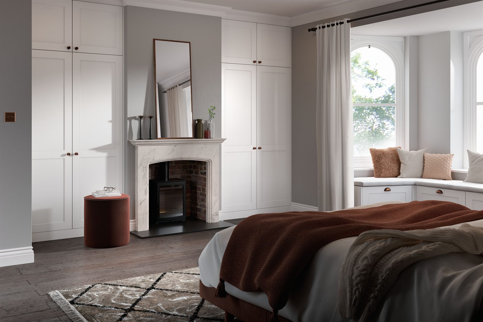 White shaker fitted wardrobes built around a marble fireplace in a bay-window bedroom